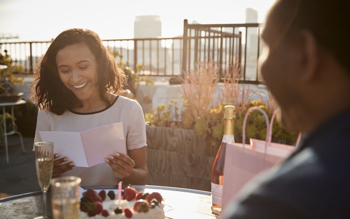 A woman lighting up as she reads a gift card
